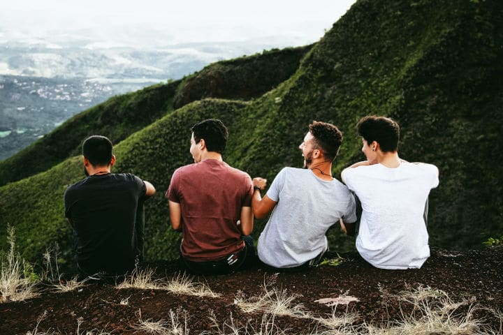four male friends sitting on mountain